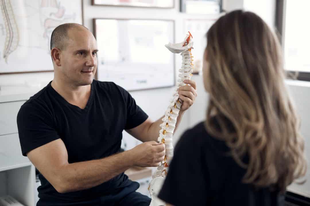 Chiropractor Dr Steven Lockstone explaining a spine model during an assessment for a Kings Cross resident