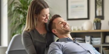 a soothing chiropractic clinic setting features a friendly chiropractor in their 30s gently treating a relaxed adult patient in smart-casual attire, surrounded by soft lighting, white walls, and timber accents, creating a calm and professional atmosphere for busy urban adults seeking effective pain relief.